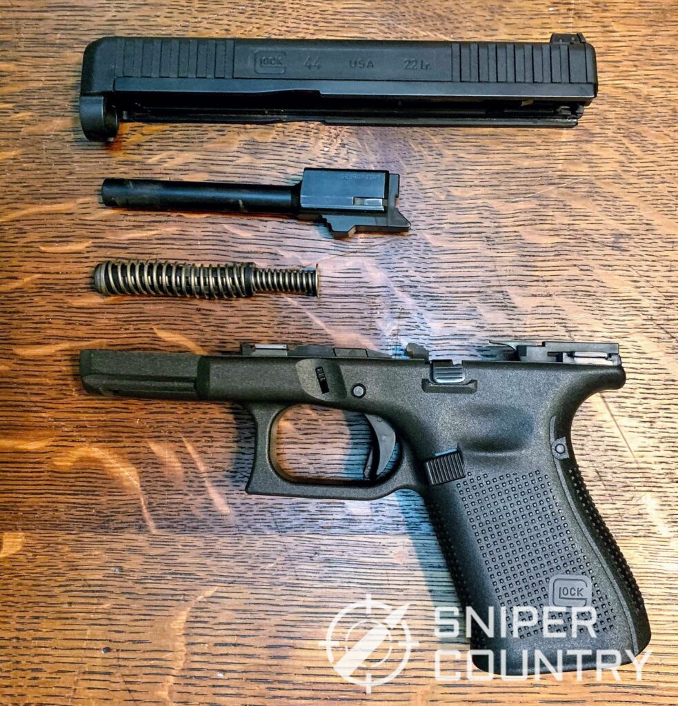 A field stripped Glock 44 showing the slide, barrel, recoil spring and receiver.