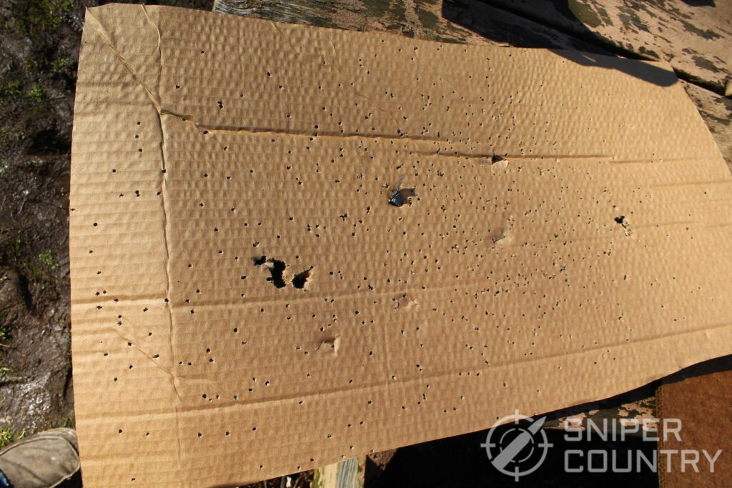 Cardboard target shot with shotshells and Winchester PDX1 Defender rounds with lead discs