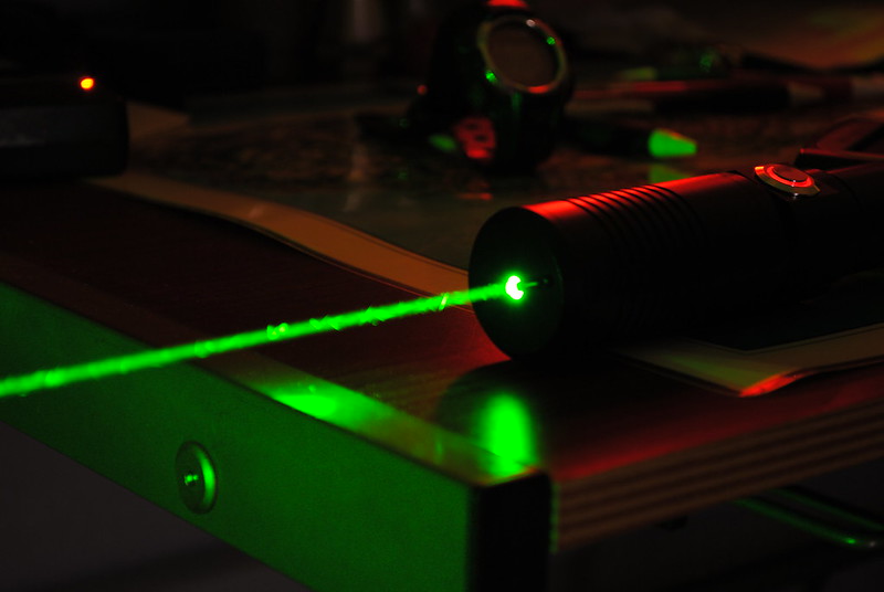 Best AR-15 Laser Sights A laser emitting green light in the dark photographed up close on the left side